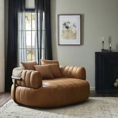 a brown leather chair sitting in front of a window on top of a white rug