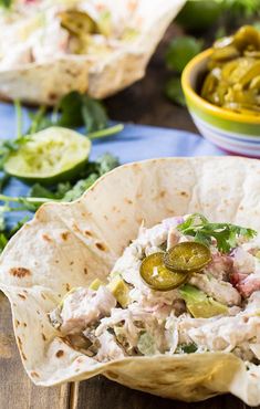 a tortilla filled with chicken and pickles on top of a wooden table