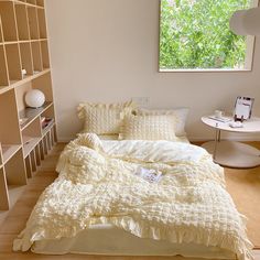 a white bed sitting in a bedroom next to a book shelf filled with lots of books