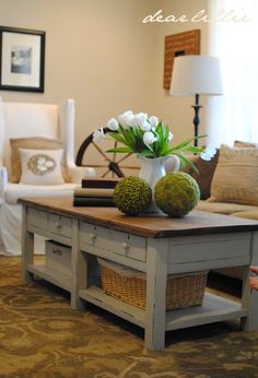 a living room filled with furniture and flowers on top of a coffee table in front of a window