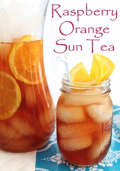 a glass jar filled with orange sun tea next to a pitcher full of lemonade