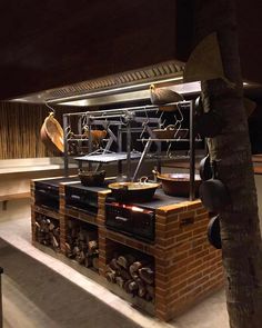 an outdoor cooking area with many pots and pans on the stove, next to a palm tree