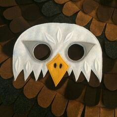 a white mask with an eagle's head on top of brown and black feathers