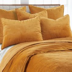 a close up of a bed with orange sheets and pillows