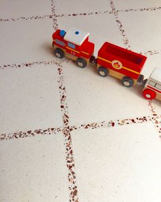 a toy firetruck is on the floor next to a toy truck that has been painted red and white