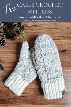 two white knitted mittens sitting on top of a wooden table next to pine cones