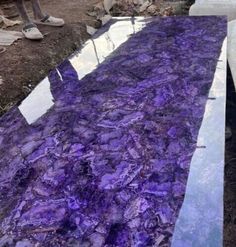 purple marble is laying on the ground in front of a man standing next to it