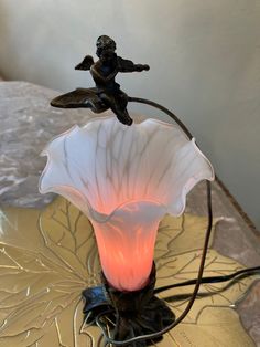 a lamp that is sitting on top of a table next to a plate with a figurine on it