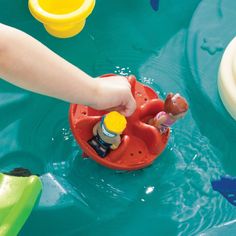 a child's hand is playing with toys in the water