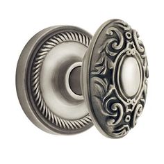 an antique style door knob with ornate design on the front and side, shown in polished silver