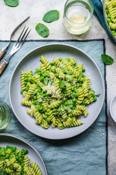 pasta with peas and parmesan cheese on a plate next to two bowls of salad