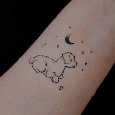 a small tattoo on the arm of a person with a dog and stars drawn on it