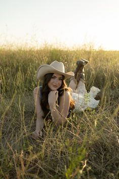 a woman wearing a cowboy hat laying in the grass