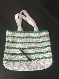 a crocheted green and white bag with a black handled knife in it's pocket