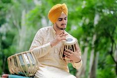 a man in a turban is playing the tabla on a wooden bench