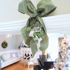 a green bow hanging from the ceiling in a living room next to a christmas tree