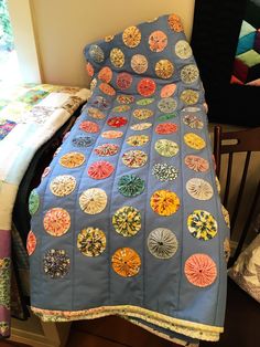 a quilted bedspread with many circular designs on it next to a chair