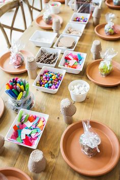 the table is set with many plates and bowls filled with candy, candies, marshmallows