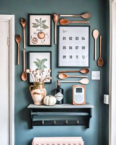 a kitchen wall with spoons, utensils and pictures on the wall above it