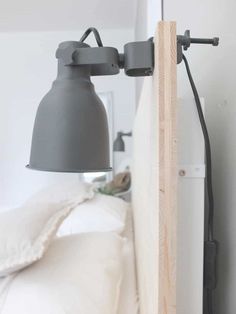 a light that is on the side of a bed next to a wall mounted lamp