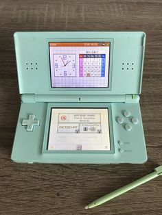 an old nintendo game system sitting on top of a wooden table next to a green pen