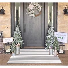 the front door is decorated for christmas with wreaths and potted trees on either side