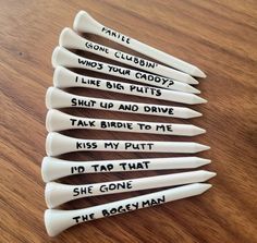 six white plastic spoons with writing on them sitting on a wooden table next to each other