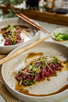 two white bowls filled with food next to chopsticks on top of a table