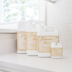 three gallon jugs sitting on top of a white counter next to a window sill