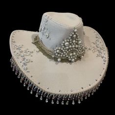 YEEHAW! Beautifully embellished with a variety of rhinestones and pearls, this hat is bound to dazzle the whole saloon! Made from a faux suede, and lined with a beautiful paisley satin, it is as beautiful on the inside as the outside!  Features rope with metal filigree ends, let them hang loose for a wide brim style hat, or tie it up on top for a western style! (see video)  Will fit up to a 60cm head circumference  Also available in other colours and styles. DM for any enquiries 🖤🐎 Note: same Custom Cowgirl Hats With Rhinestones, Hat With Rhinestone Fringe, Cheap Hat Bands For Western-themed Events, Festival Hat With Rhinestones And High Crown, Festival Hats With Rhinestones And High Crown, Elegant Embellished Hats For Festival, Elegant Rhinestone Hats For Festival, Elegant Rhinestone Festival Hats, Boho 2024