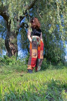 a woman standing under a tree with her hands in her pockets and looking at the ground