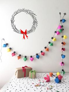 a decorated christmas wreath and presents on a bed with polka dot tablecloth, streamers and paper garlands