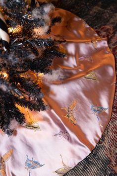 a christmas tree skirt with butterflies on it and a pen in the top right corner