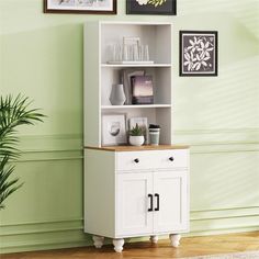 a white cabinet with drawers and pictures on the wall