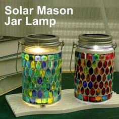 two glass jars sitting next to each other on top of a table with the words solar mason jar lamp