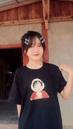 a woman with black hair wearing a t - shirt that has an anime character on it