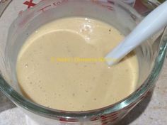 a glass bowl filled with batter on top of a counter next to a plastic spoon