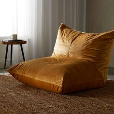 a brown chair sitting on top of a rug next to a table with a cup