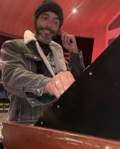 a man standing next to a piano in a recording studio with his hand on the keyboard