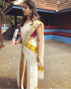 a woman in a white and yellow sari is talking to someone on the sidewalk