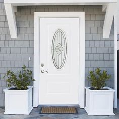 a white front door with two planters on the side