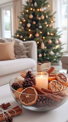 a glass bowl filled with orange slices and cinnamons on top of a table next to a christmas tree