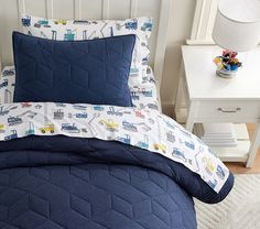 a bed with blue and white comforters in a bedroom next to a night stand