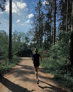 a man running down a dirt road in the woods