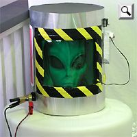 a green alien face on a black and yellow striped bucket sitting on top of a white crib