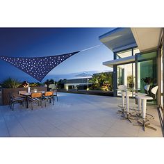 an outdoor dining area is lit up with blue and white polka dotes on the awning