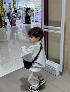 a little boy standing in front of a store