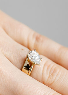 a woman's hand with a diamond ring on top of her finger, showing the center stone