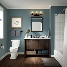 a white toilet sitting next to a sink in a bathroom under a framed mirror on a wall