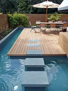 a wooden deck next to a swimming pool with steps leading up to an outdoor dining area